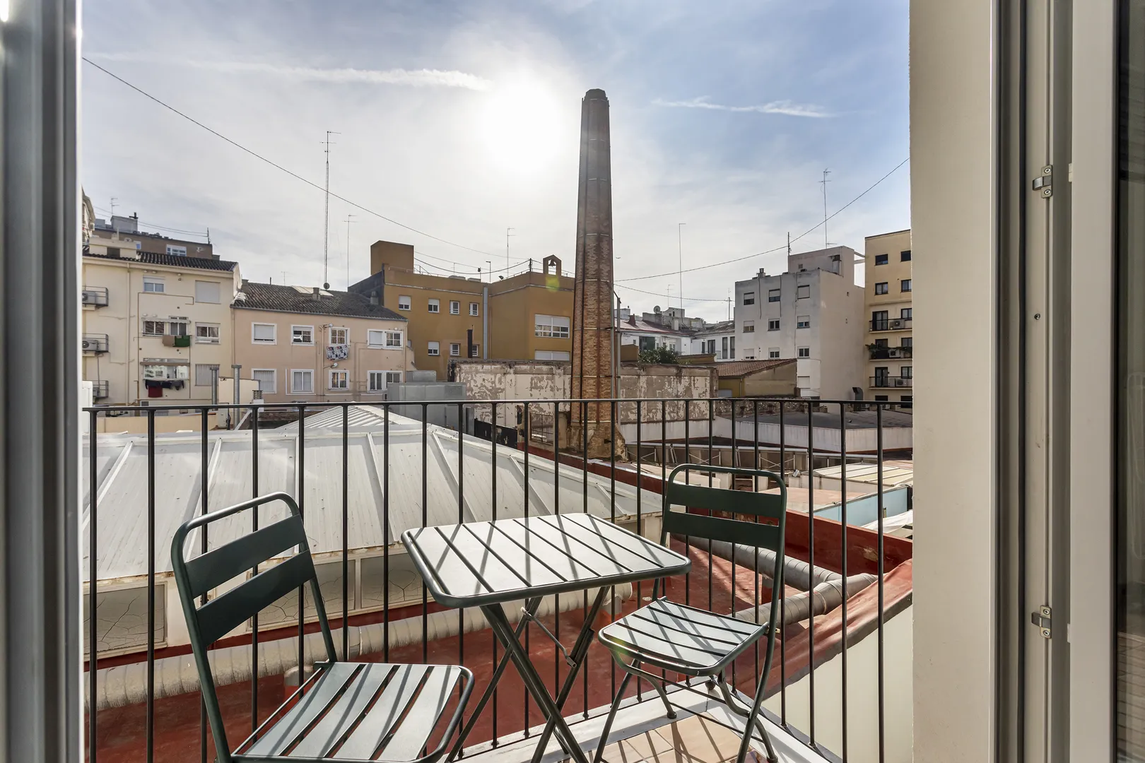 Varanda com mesa e duas cadeiras junto de edifícios urbanos