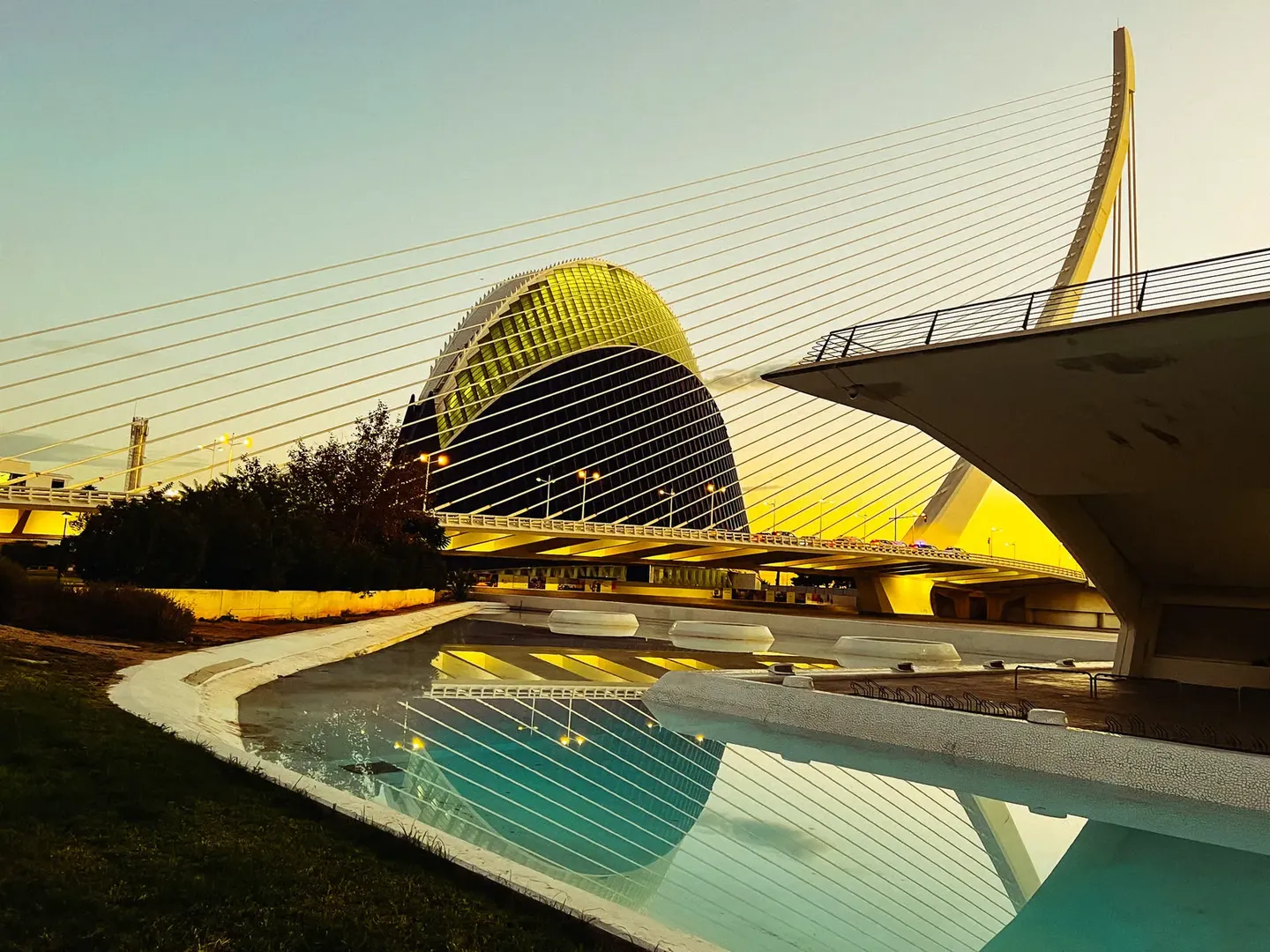 Hemisfèric e ponte refletidos na água ao entardecer