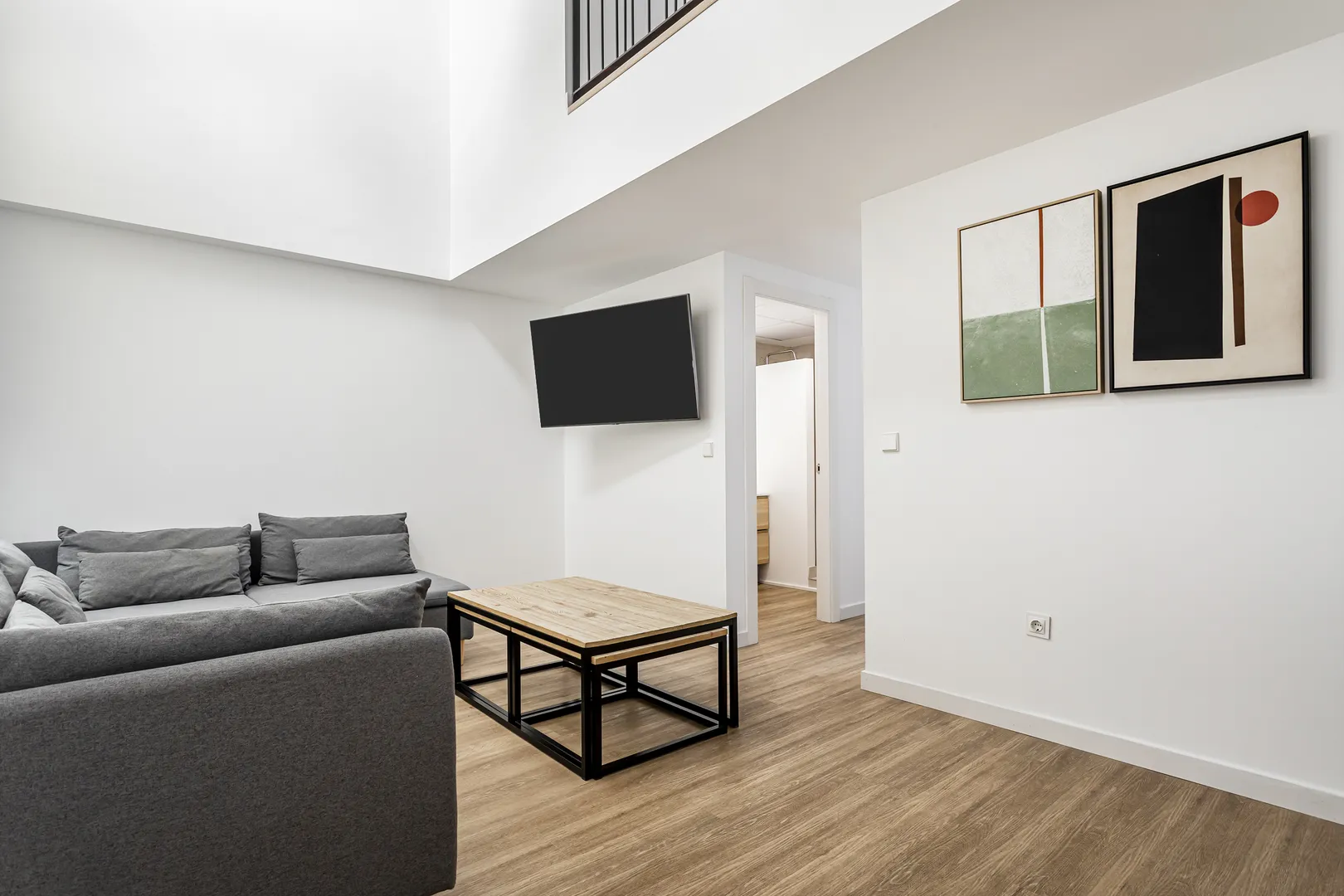 Sala com sofá cinzento, mesas de centro e televisão
