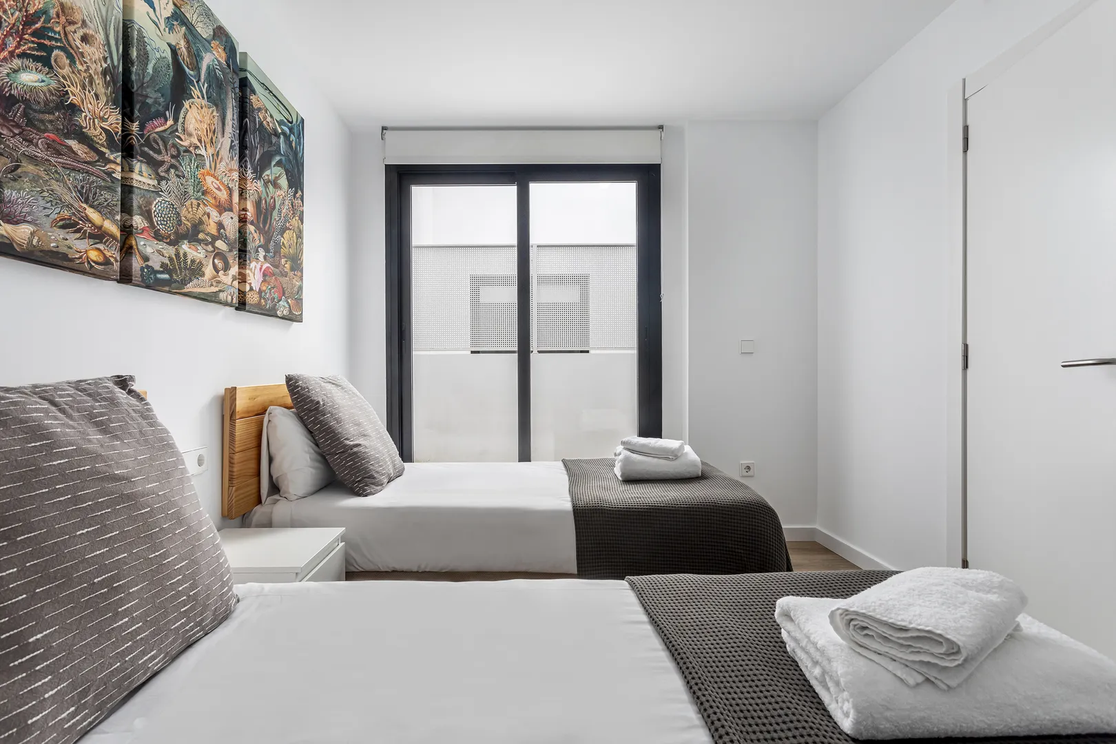 Quarto luminoso com duas camas individuais e roupeiro branco