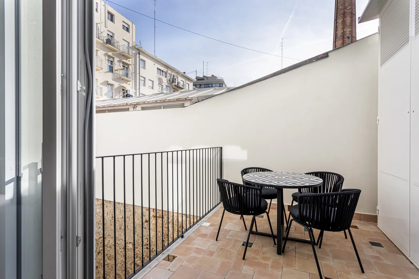 Pequeno terraço com mesa redonda e cadeiras pretas