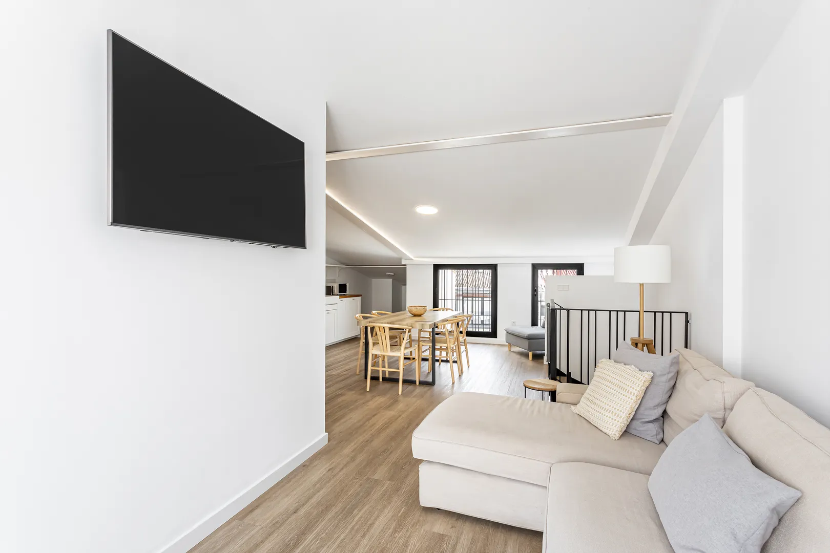 Sala com sofá claro e mesa de refeições ao fundo