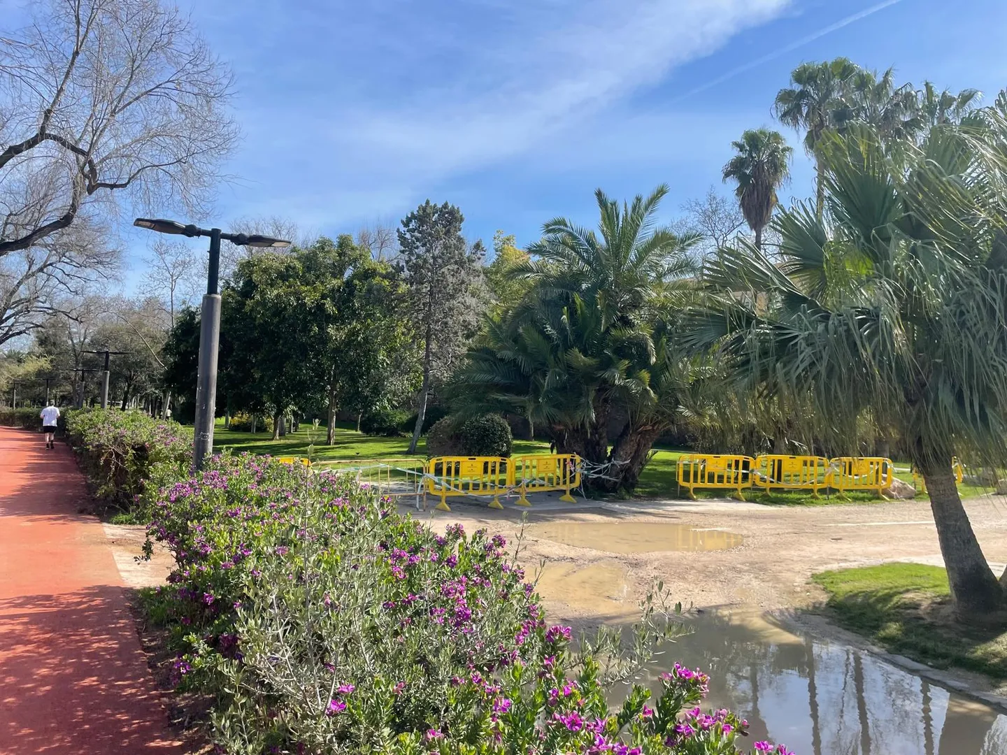 Jardim com flores, palmeiras e uma ponte ao fundo
