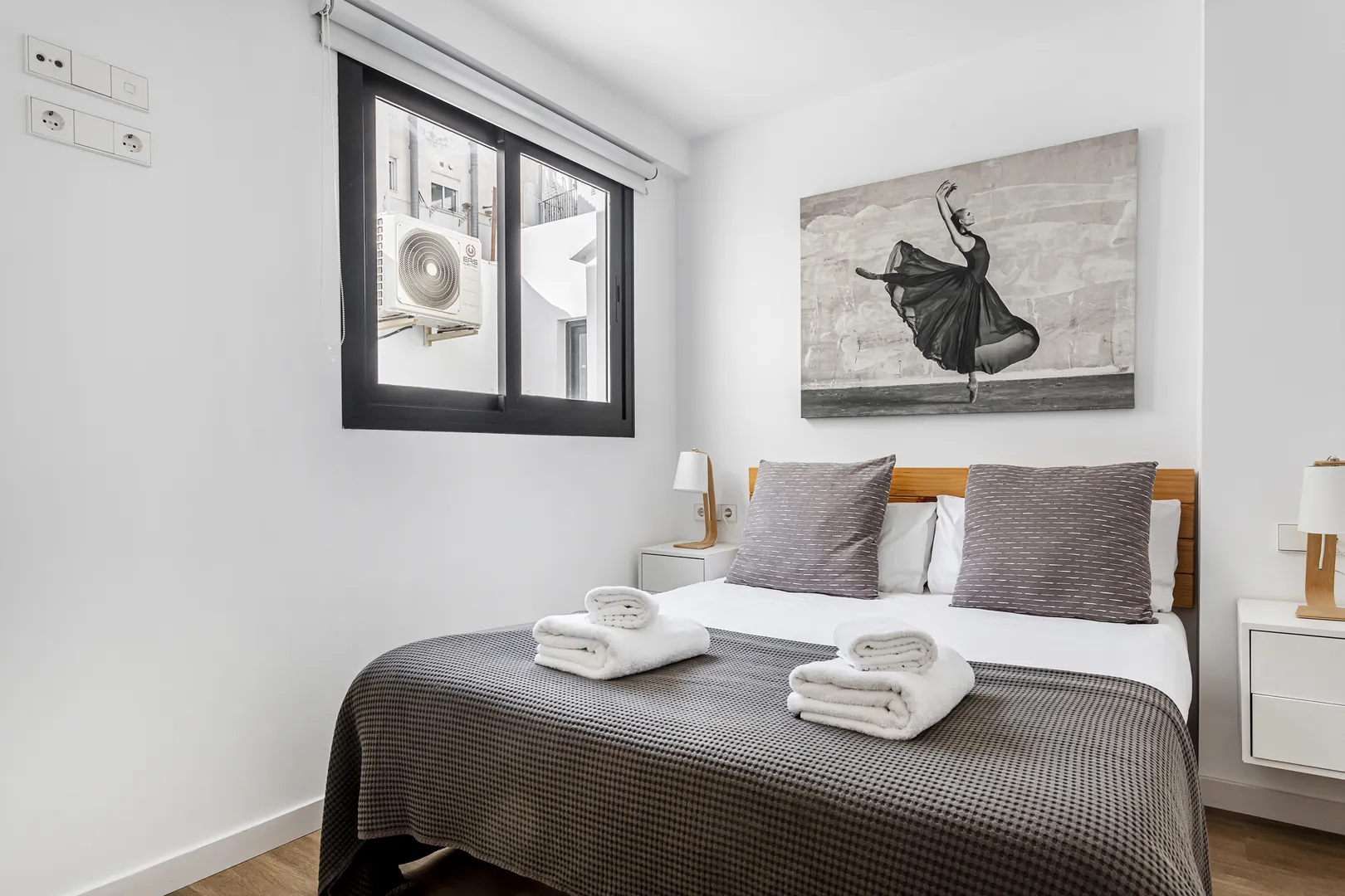 Quarto com cama de casal, janela e toalhas preparadas