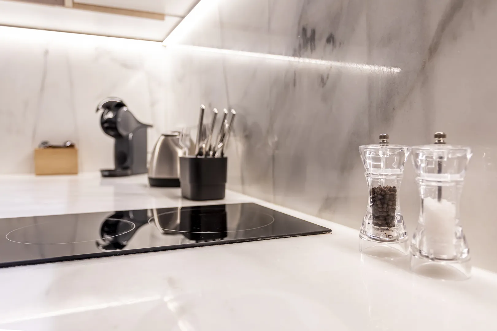 Bancada de cozinha com placa, utensílios e pequenos recipientes